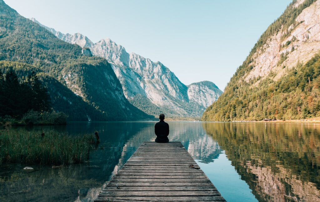 man sitting on gray dock