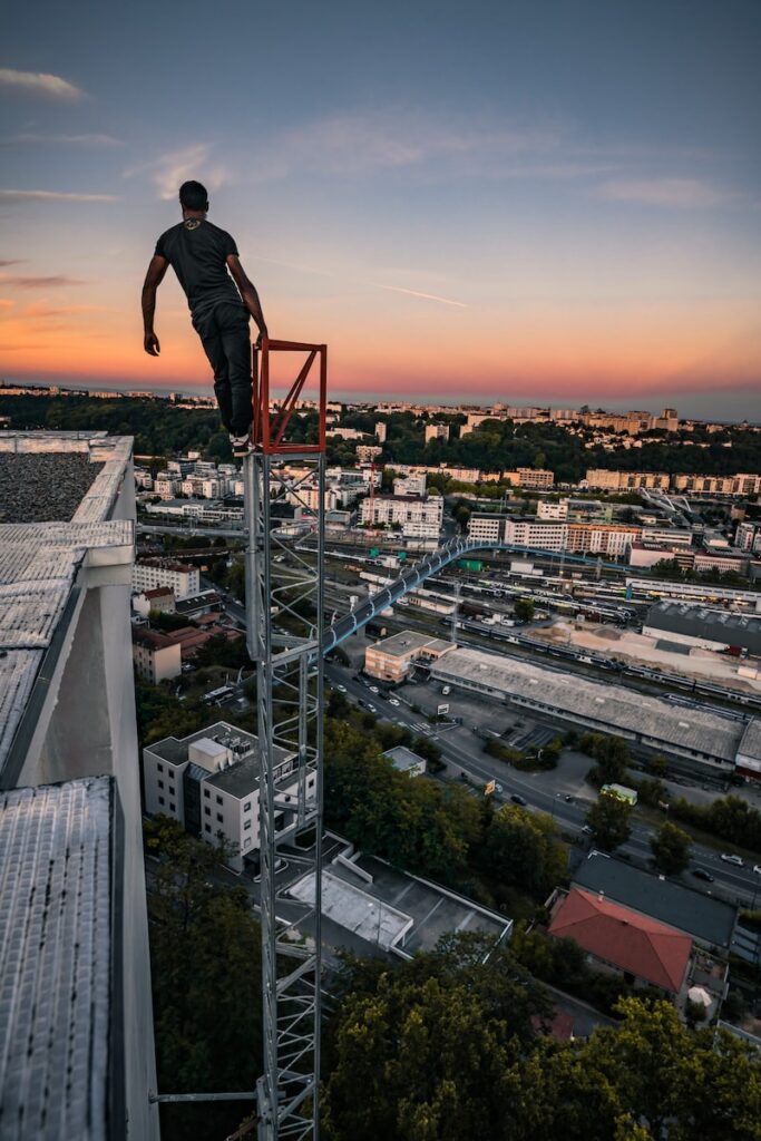 entretenir l'amour man in black jacket and pants standing on top of building during sunset