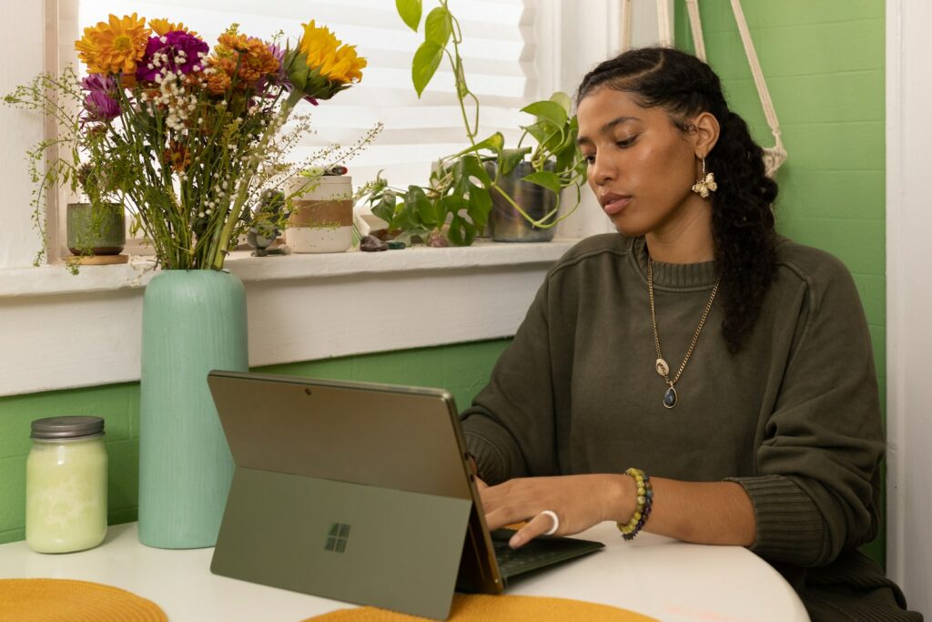 a woman sitting at a table using a laptop computer améliorer sa concentration stay focus