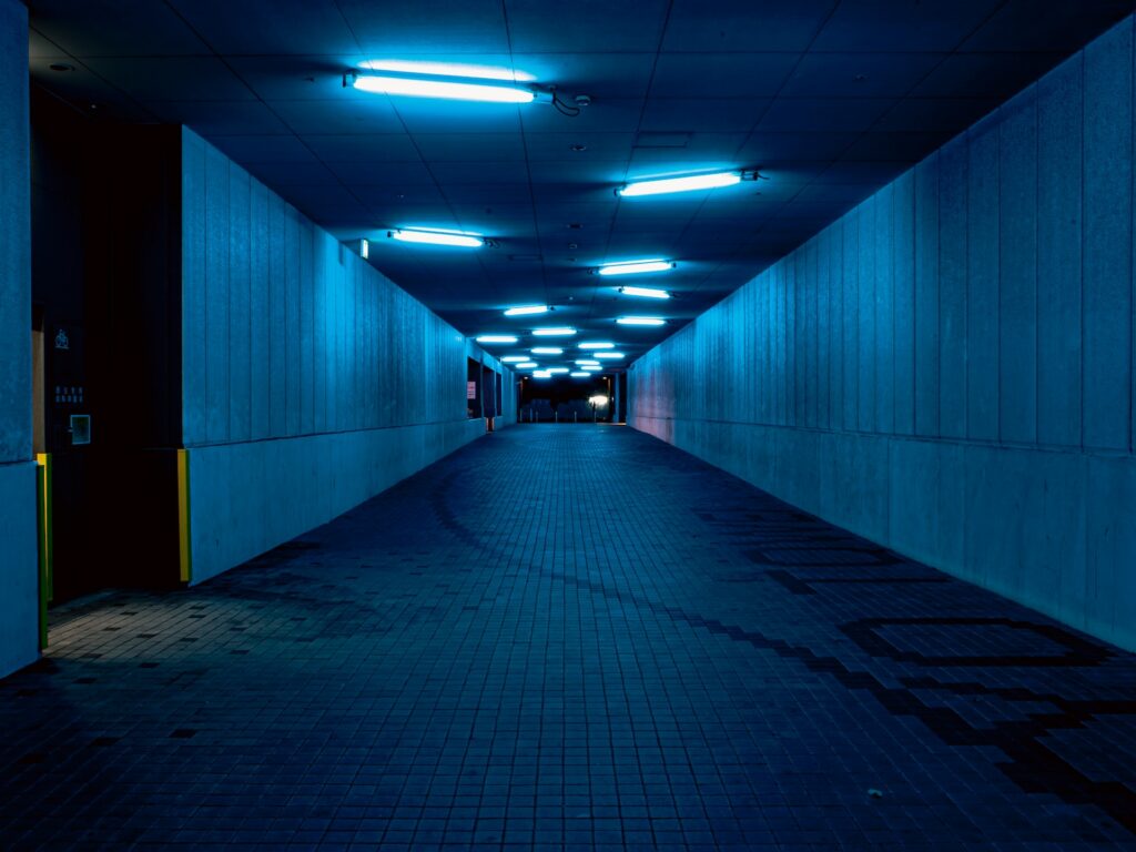 a long dark hallway with blue lights on the ceiling, on m'a trahi je souffre
