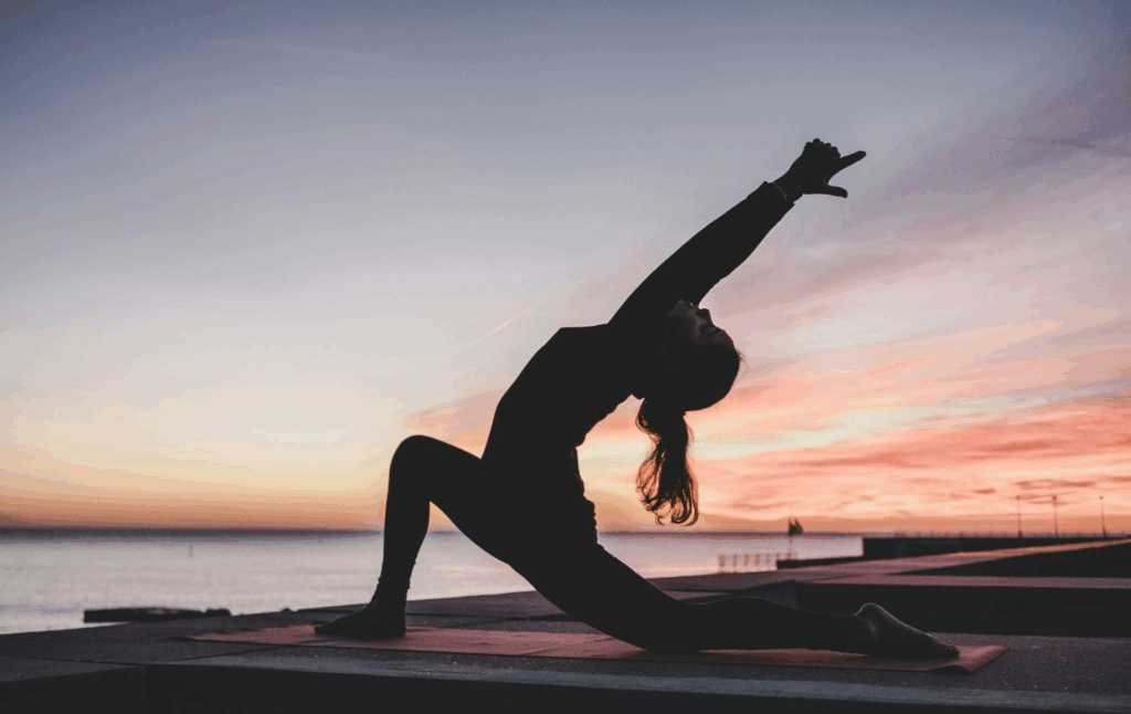 Coup de blues : comment l’identifier et s’en libérer naturellement Femme au bord de l'eau qui effectue une position de yoga