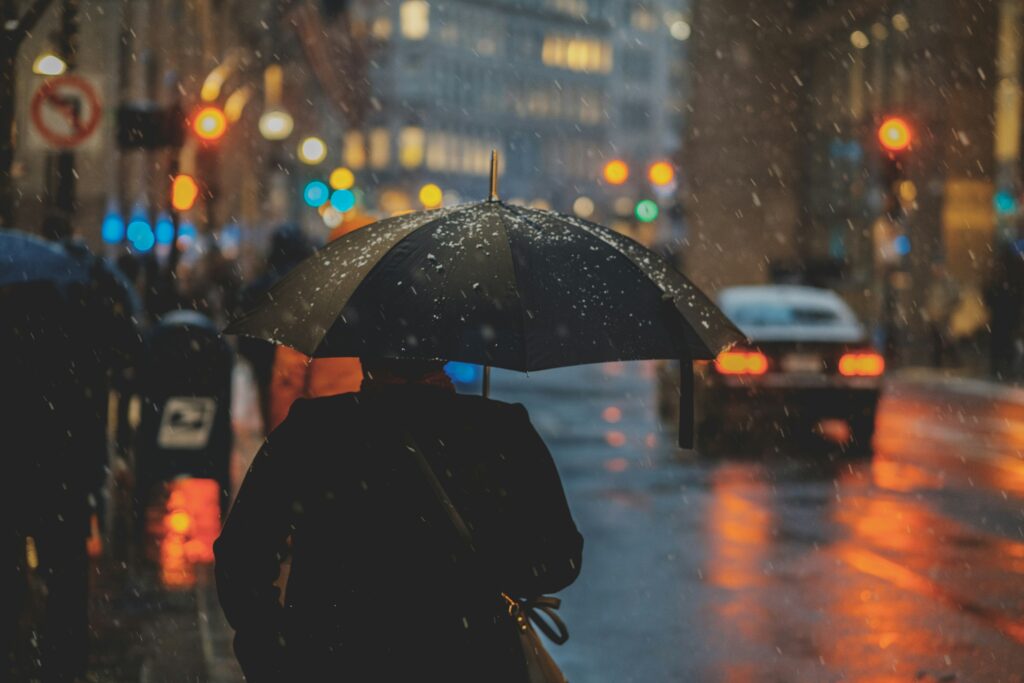 Coup de blues : comment l’identifier et s’en libérer naturellement Une personne de dos marche dans la rue avec un parapluie. Le temps est pluvieux.
