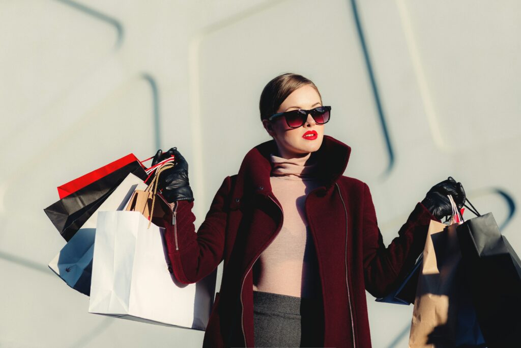 Photo d'une femme qui vient de faire du shopping et qui tient dans ses mains de nombreux sacs. Cette photo exprime les achats impulsifs.