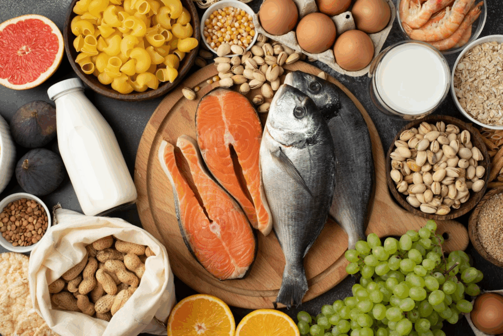 Aliments Anti-Stress : Votre Arme Naturelle Contre l'Anxiété au Quotidien Photo d'une table sur laquelle se trouvent de nombreux aliments anti-stress (poisson, raisins, pistaches).