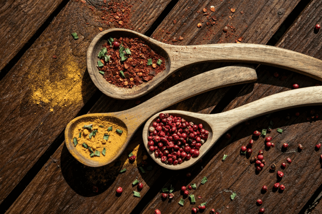 Aliments Anti-Stress : Votre Arme Naturelle Contre l'Anxiété au Quotidien Image de 3 cuillères en bois posées sur une table. Chaque cuillère contient des épices différentes